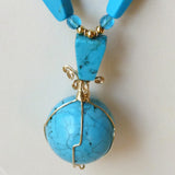 detail of blue chalk turquoise with sphere and gold filled wire