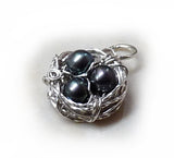 Bright silver wire nest with dark freshwater pearl eggs.